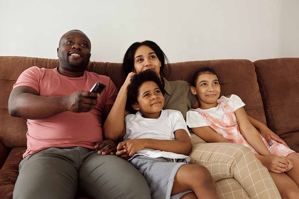 Family Sitting On Couch Watching Movied