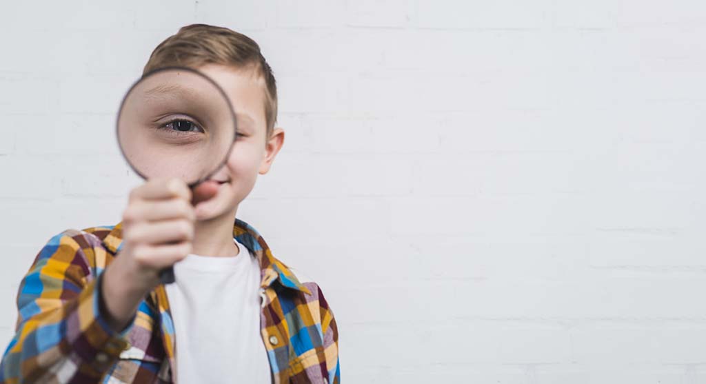 Boy On Scavenger Hunt Looking Trough Magnifying Glass