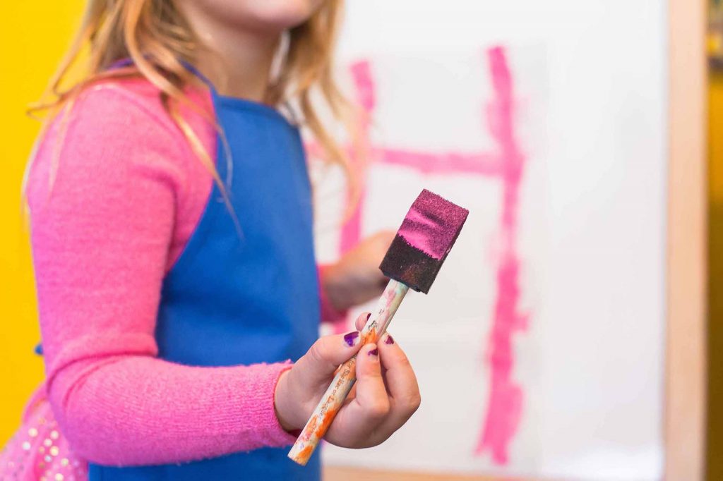 Young Girl Holding Sponge Brush With Pink Paint