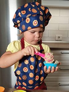 Young Girl Wearing RiseBrite Blue Cookies Apron Scooping Cupcake Batter
