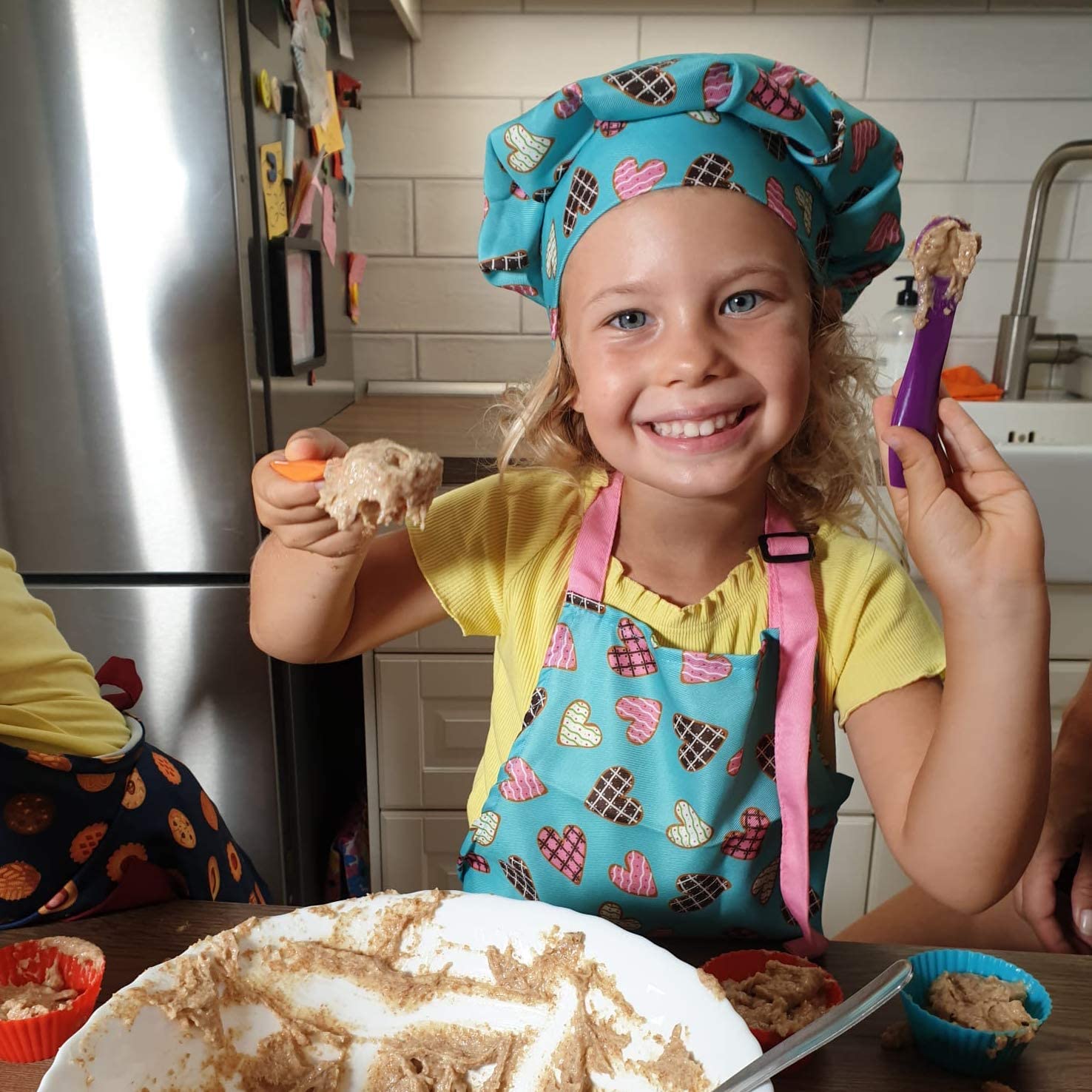 Young Girl Baking While Wearing RiseBrite Pink Heart Apron And Chef Hat